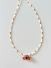 Necklace with white beads and a poodle dog pendant on a light gray background