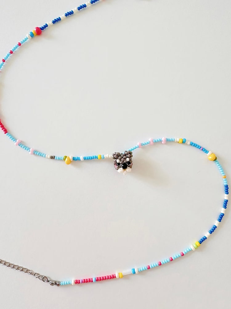 Colorful beaded necklace with a small Schnauzer dog pendant on a light gray background