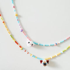 Colorful beaded necklaces with small CAT charms on a light gray background