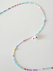 Colorful beaded necklace with a small white cat on a light gray background