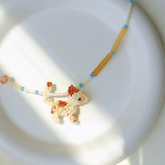 Beaded necklace with a Calico cat-shaped pendant on a white plate