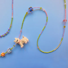 Colorful beaded necklace with a handmade Westie dog-shaped charm on a blue background