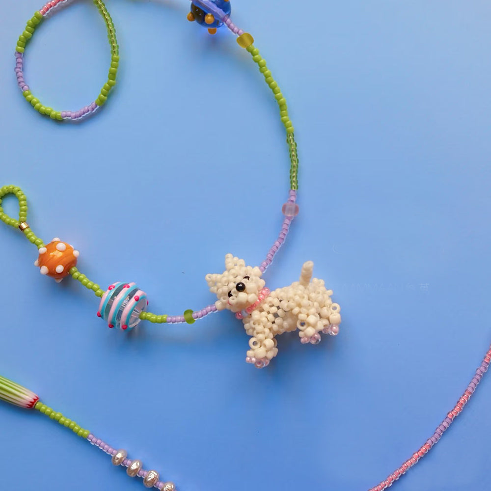 Beaded Westie dog charm on a colorful string against a blue background