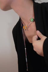 Person wearing a necklace with beaded Shiba Inu charm on a plain background
