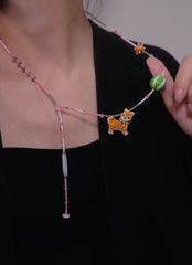 Necklace with a beaded Shiba Inu charm held by a hand against a black background