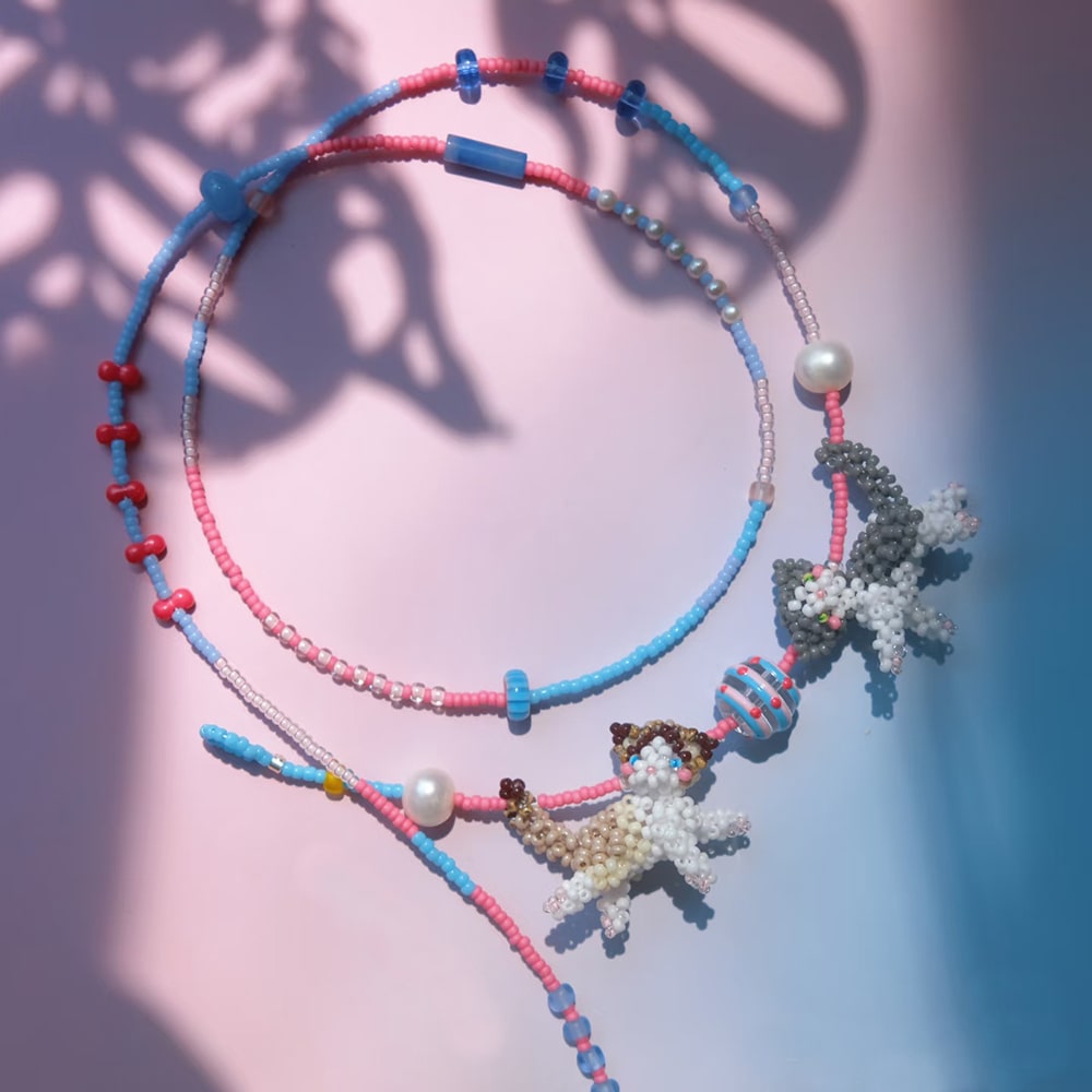 Colorful beaded necklaces with couple cats charms on a gradient background
