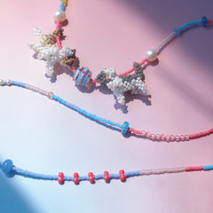Colorful beaded necklace with couple cats pendant on a pink background