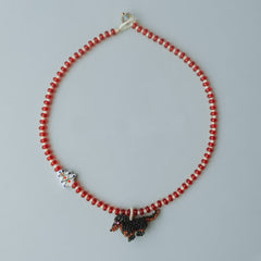 Handmade Necklace with red beads and a Dachshund  dog charm on a gray background - verhalo jewelry