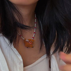 Close-up of a person wearing a handmade necklace with a poodle dog pendant. - verhalojewelry