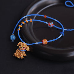 Blue beaded necklace
 with a cocker spaniel dog charm on a dark surface - verhalo jewelry