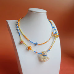 Colorful beaded necklace with a british shorthair ppendant on a mannequin against an orange background