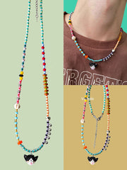 Colorful beaded necklace with a black cat charm on a green background - Verhalo handmade jewelry