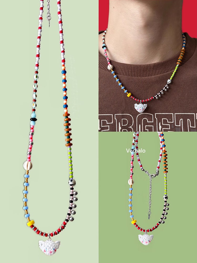 Colorful beaded necklaces with white cat charm on a green background - Verhalo handmade jewelry