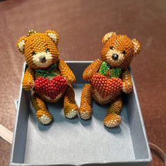 Two teddy bear figurines with heart and decorations on a brown surface.