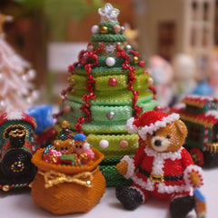 beaded Christmas tree with decorations and a Santa figure on a blurred background