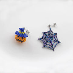 Two beaded earrings, one shaped like a pumpkin and the other like a spider web, on a white background.