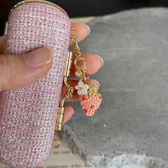Pink glittery phone case with a decorative keychain featuring a strawbe charm.