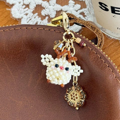 Decorative charms with beads and gold elements on a brown leather bagsurface