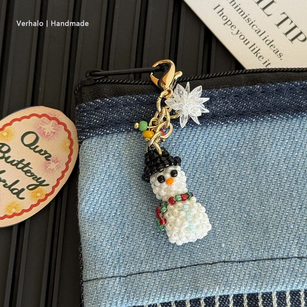 Snowman bag charm with decorative elements on a denim surface, with 'Verhalo Handmade' label.