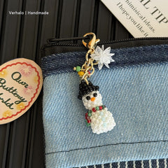 Snowman bag charm with decorative elements on a denim surface, with 'Verhalo Handmade' label.