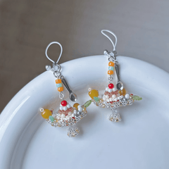 Colorful beaded pudding boat phone harm on a white plate with a gray background
