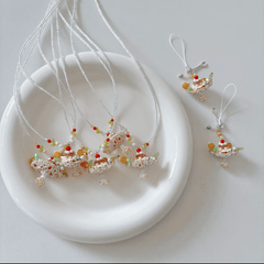 Decorative necklaces with colorful pudding boat cake and pudding boat phone charm on a white plate