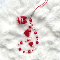 Beaded cake phne strap with red and white beads on a white fur background