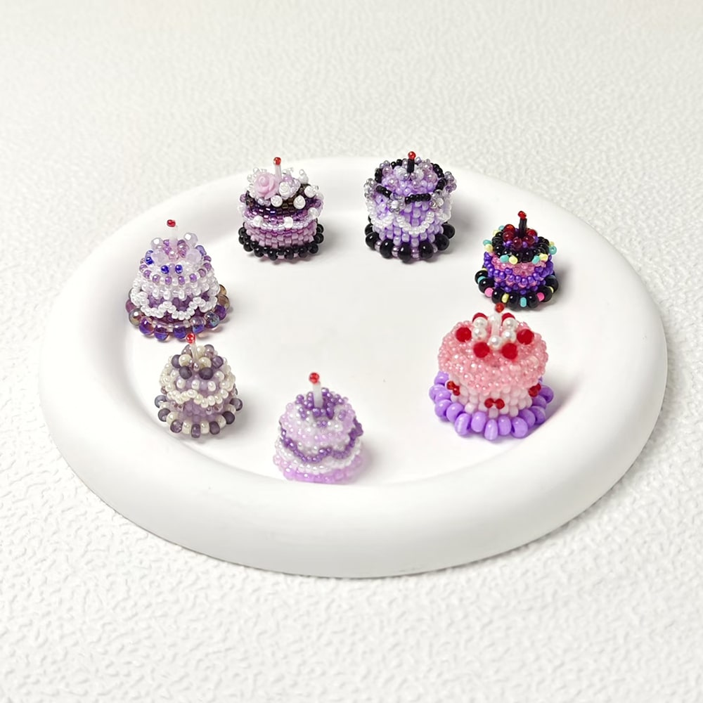 Set of beaded cake charms on a white plate with a white background