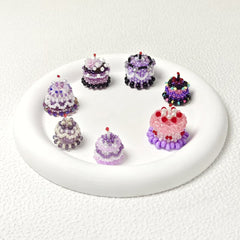 Set of beaded cake charms on a white plate with a white background