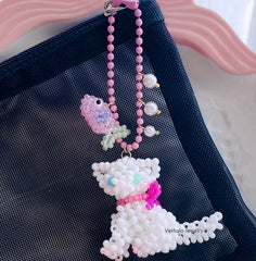 Beaded white cat charm with pink bow on a dark blue background丨Verhal Custom Jewelry