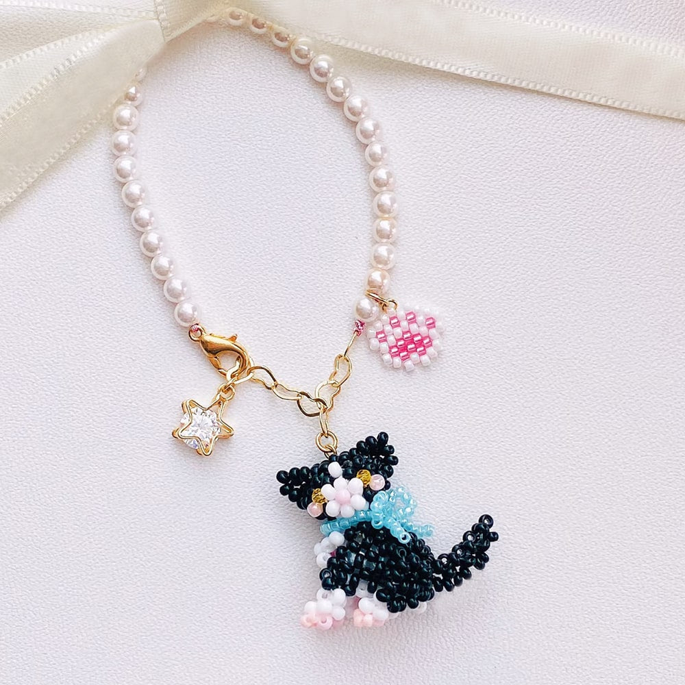 Pearl bag charm with a black cat charm on a white background
