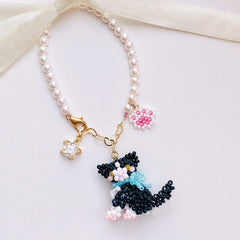 Pearl bag charm with a black cat charm on a white background