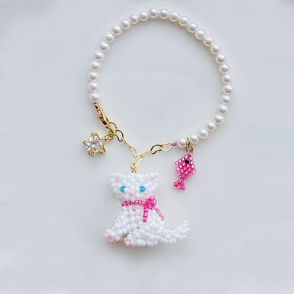 Pearl bag charm with a cat charm on a light gray background