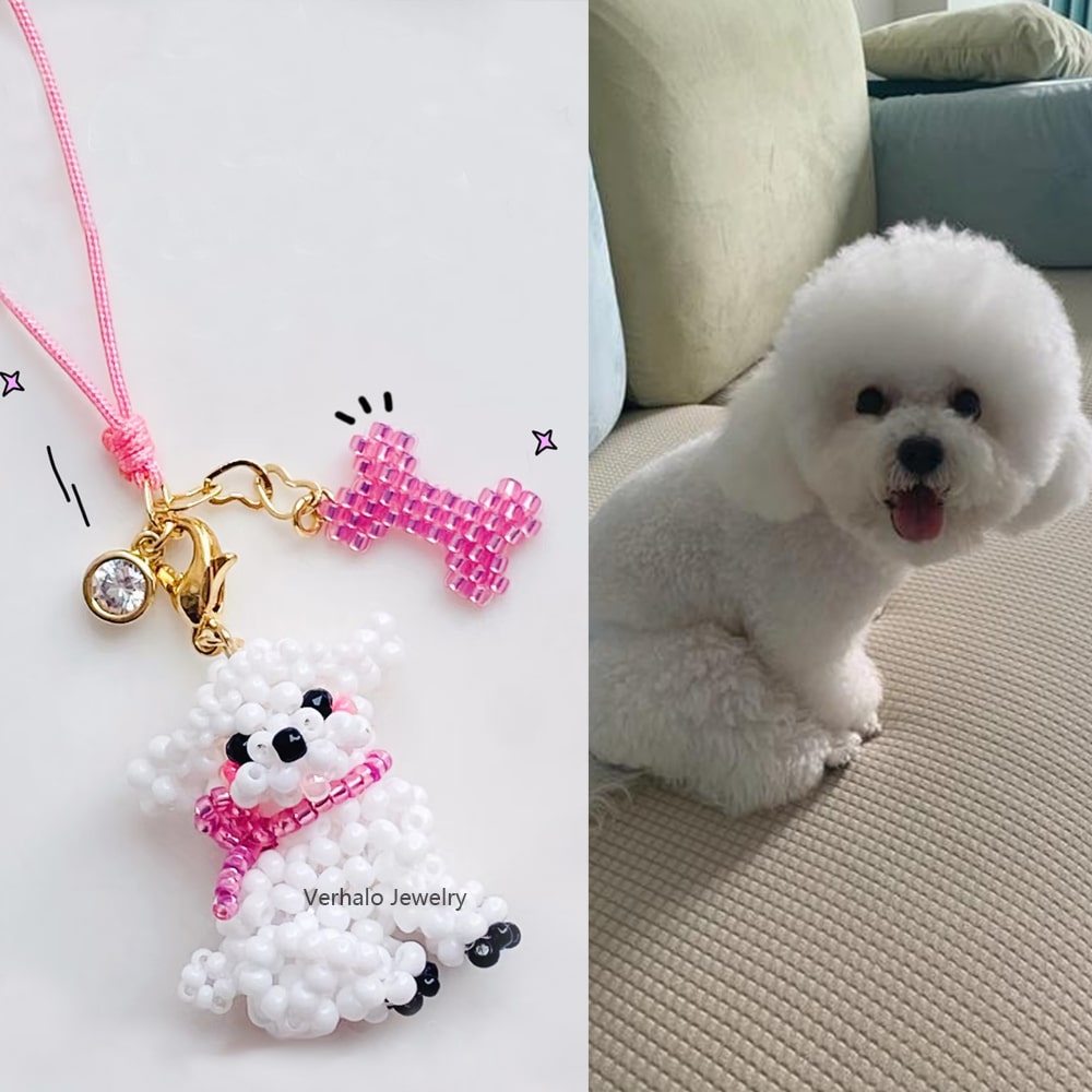 White bichon dog sitting on a couch next to a beaded charm with a pink bow and gold accents. - verhalo custom jewelry
