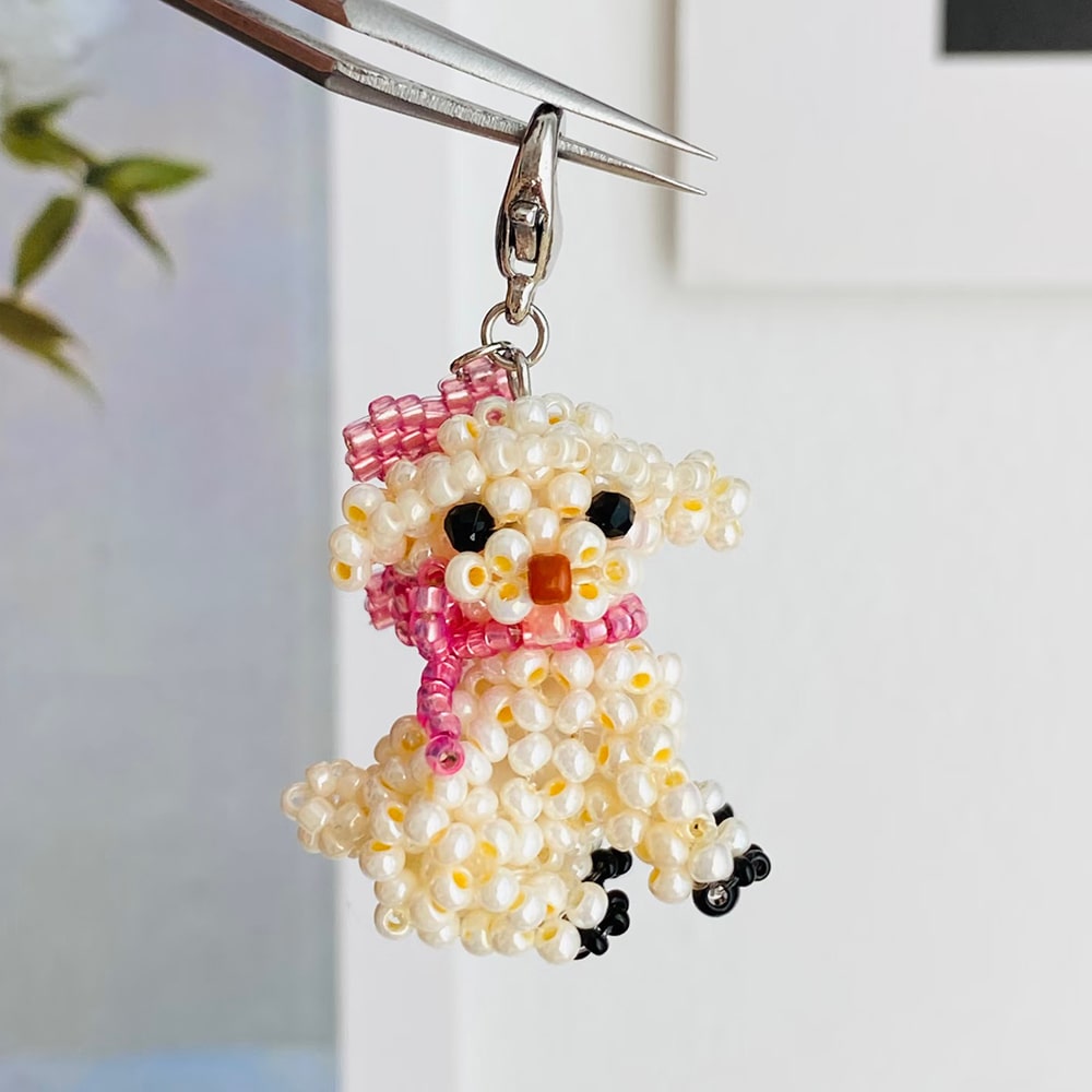 Beaded dog-shaped keychain with a pink scarf on a white background