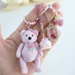 Hand holding a pink beaded teddy bear keychain with accessories on a light background - Verhalo jewelry