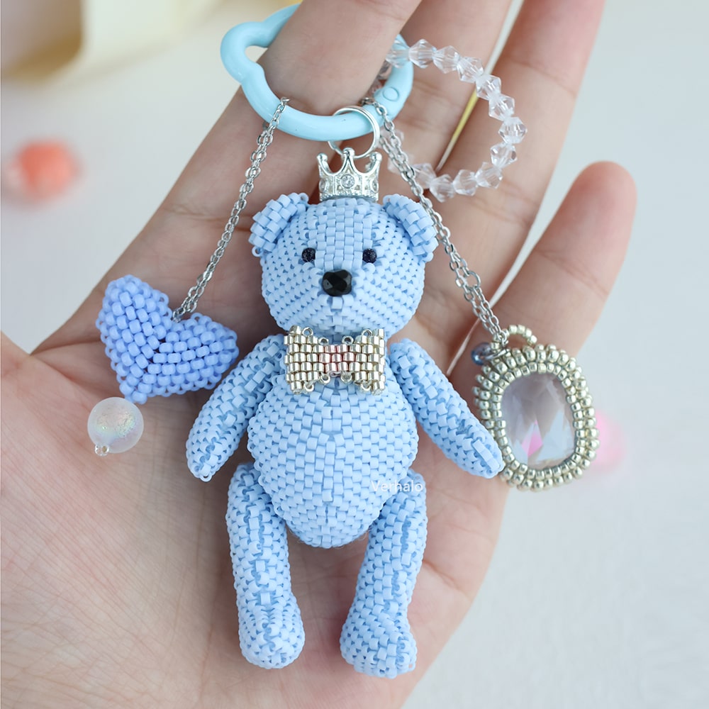 Blue beaded teddy bear keychain with accessories on a hand against a light background - verhalo handmade jewelry