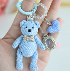 Blue teddy bear keychain held in a hand with a blurred background - Verhalo jewelry