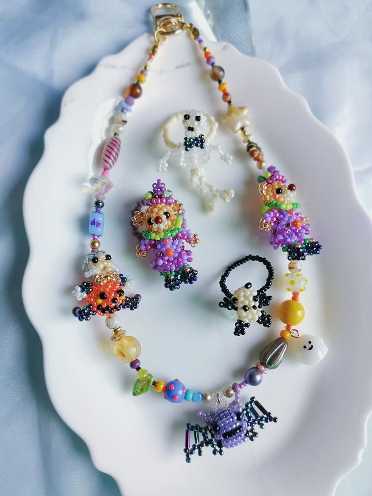 Colorful beaded halloween phone cahrm with various charms on a white shell