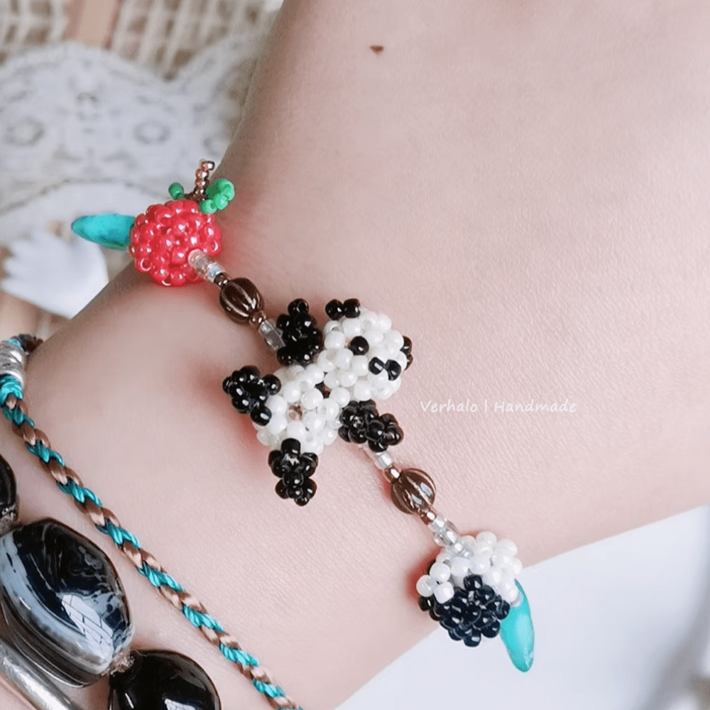 Close-up of a beaded bracelet with panda design on a wrist.