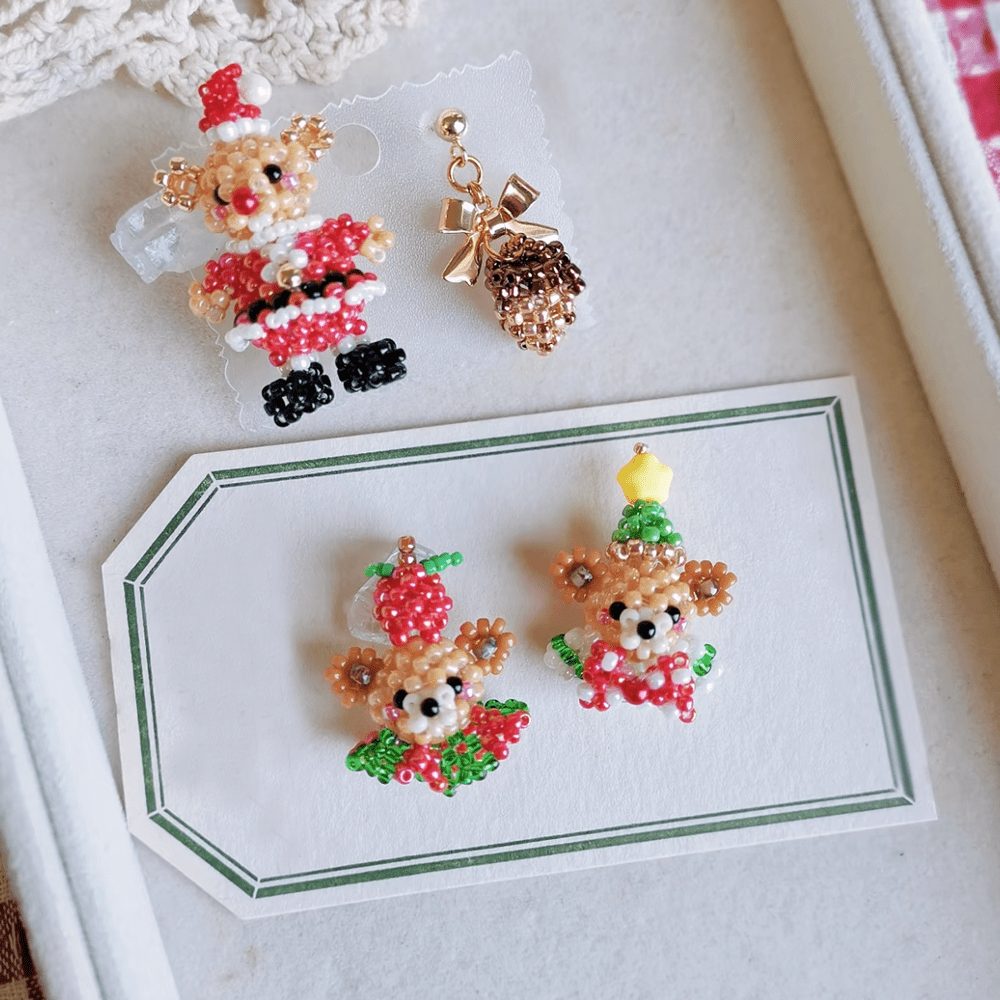 Two pairs of Christmas Bear Stud earrings on a white card with a green border.