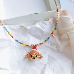 Colorful beaded necklace with a small dog pendant on a white fabric background