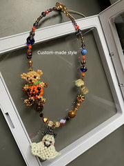Beaded charm with teddy bear and ghost design on a clear stand.