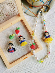 Colorful character earrings and keychain on a textured surface