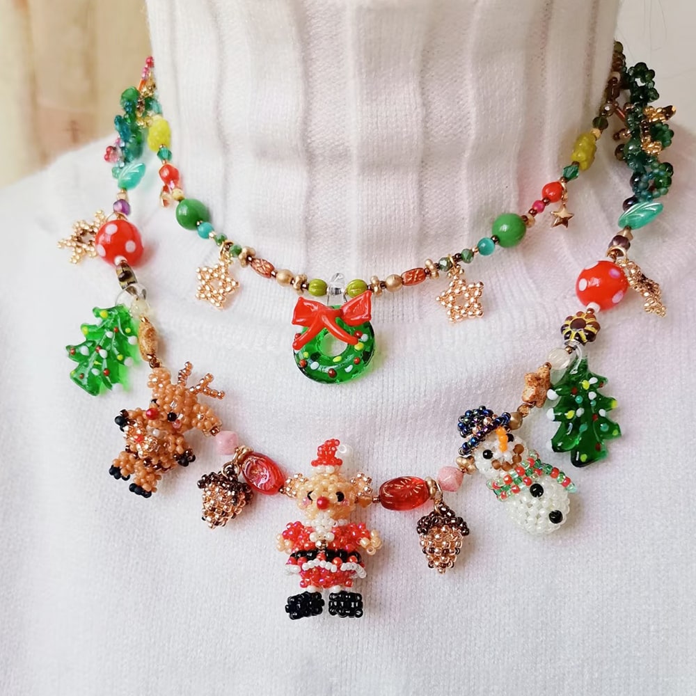 Colorful beaded necklace with Christmas-themed charms on a white fabric background
