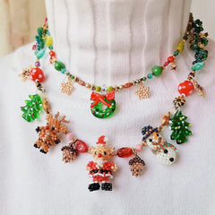 Colorful beaded necklace with Christmas-themed charms on a white fabric background