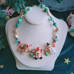 Handmade Colorful beaded Christmas spirit necklace with snowman, Santa,  Gingerbread Man figures on a white stand.- verhalo custom jewelry