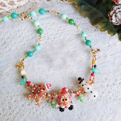 Handmade Colorful beaded Christmas spirit necklace with snowman, Santa,  Gingerbread Man figures on a textured white surface- verhalo custom jewelry