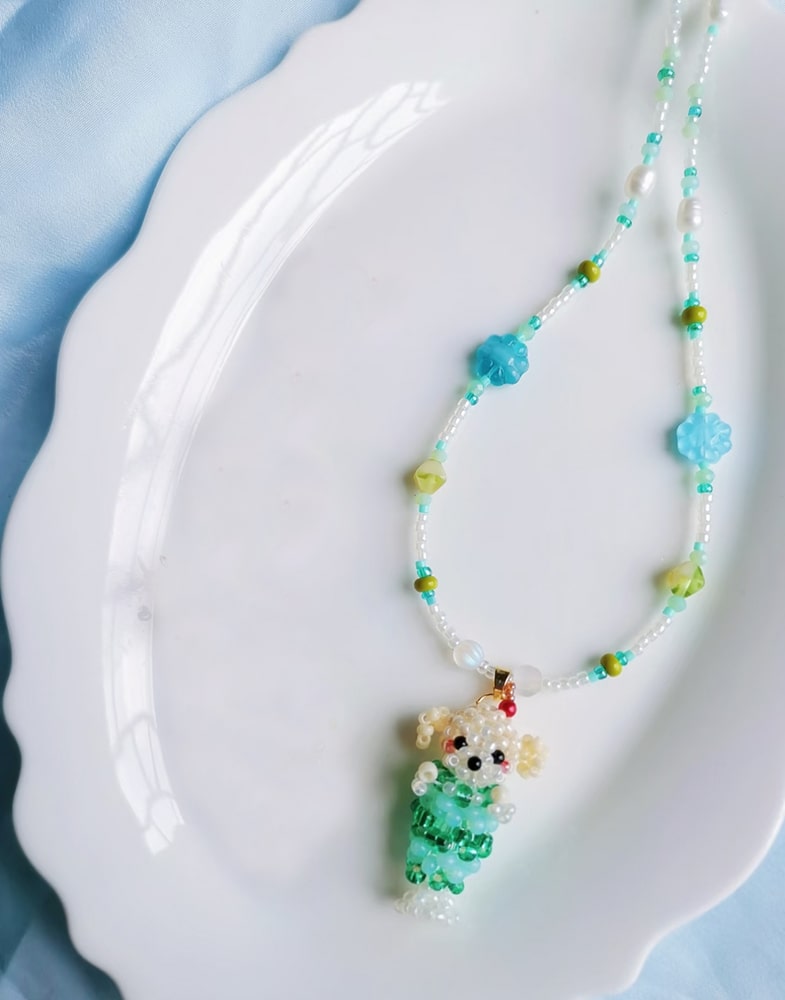 Colorful beaded necklace with a small dog pendant on a white plate
