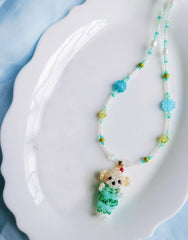 Colorful beaded necklace with a small dog pendant on a white plate